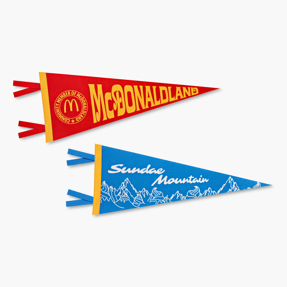 One gold and red McDonaldland pennant flag next to a blue, gold, and white Sundae Mountain pennant flag