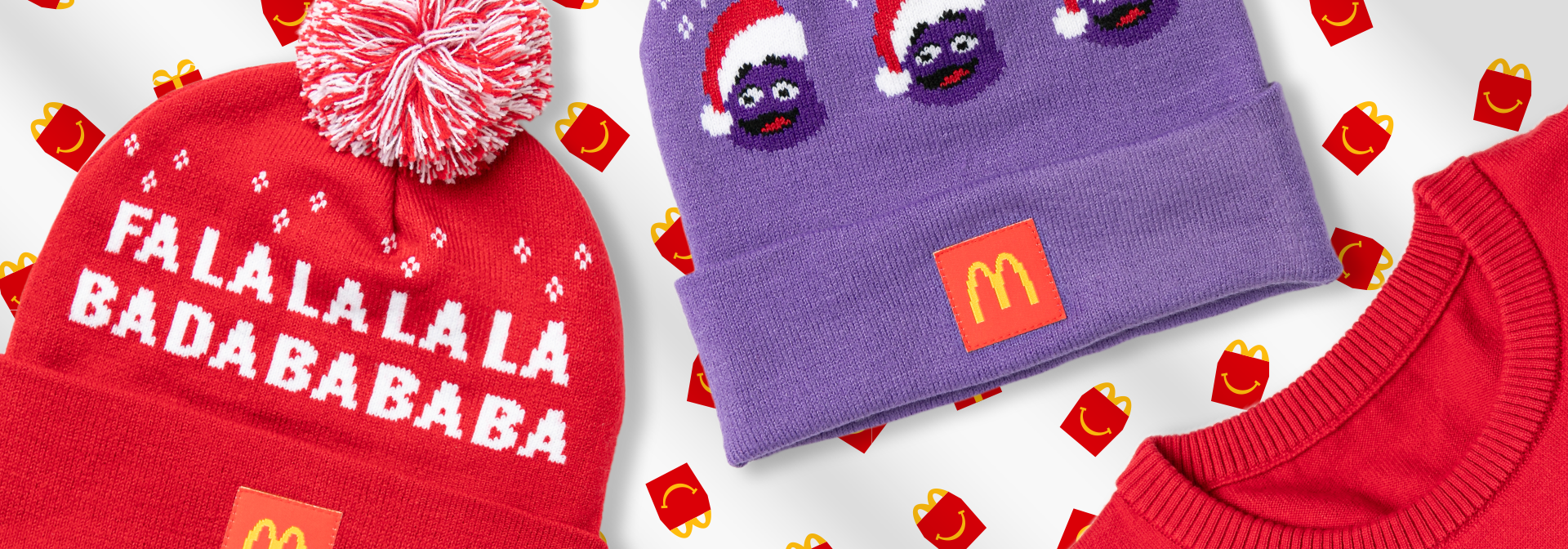McDonald's-themed winter apparel on Happy Meal wrapping paper: red knit hat with 'FALALALALA BADABABABA' text, purple beanie with Grimace and logo patch, and red ribbed sweater.