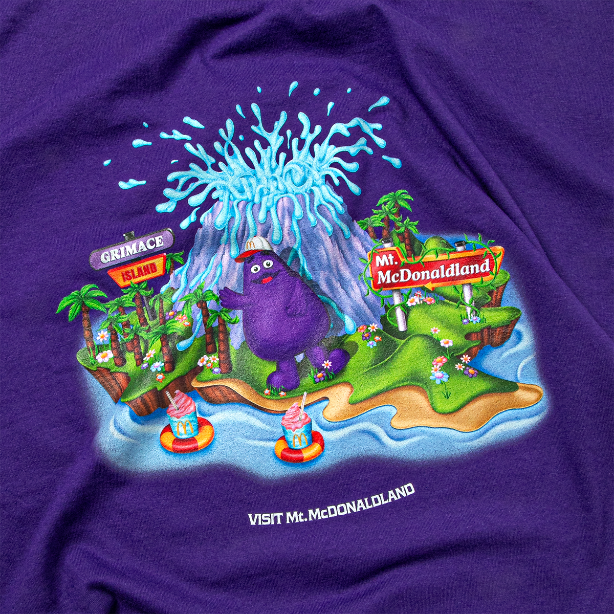 Close-up view of Grimace Island featuring an erupting blue shake volcano, palm trees, and two blue and pink Mt. McDonaldland shakes floating in water tubes