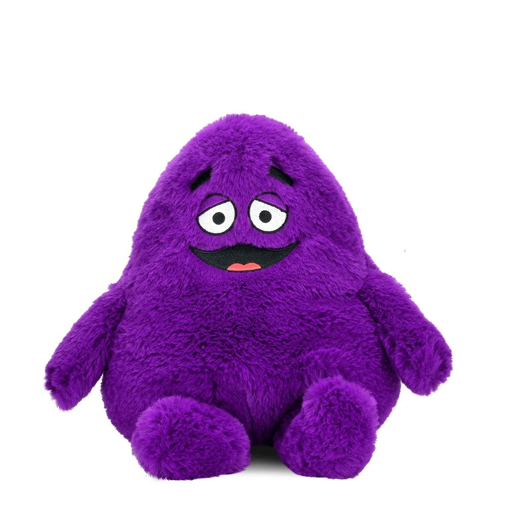 Front view of the Grimace Phunny Plush by Kidrobot, featuring a purple plush character with embroidered eyes, eyebrows, smile, and seated legs.