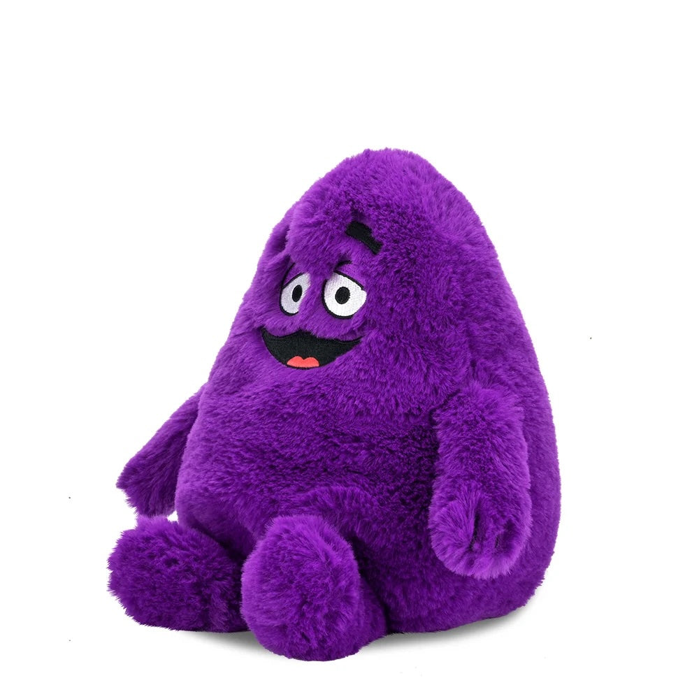 Side angled view of the Grimace Phunny Plush by Kidrobot showing the Grimace plush seated with embroidered facial details.