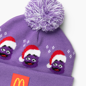 Front close-up of beanie with purple-and-white pom, three Grimaces in red and white hats framed by tiny snowflakes, and the Golden Arches patch.