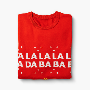 Folded view showing pixelated white text and tiny snowflake accents on red holiday sweater.